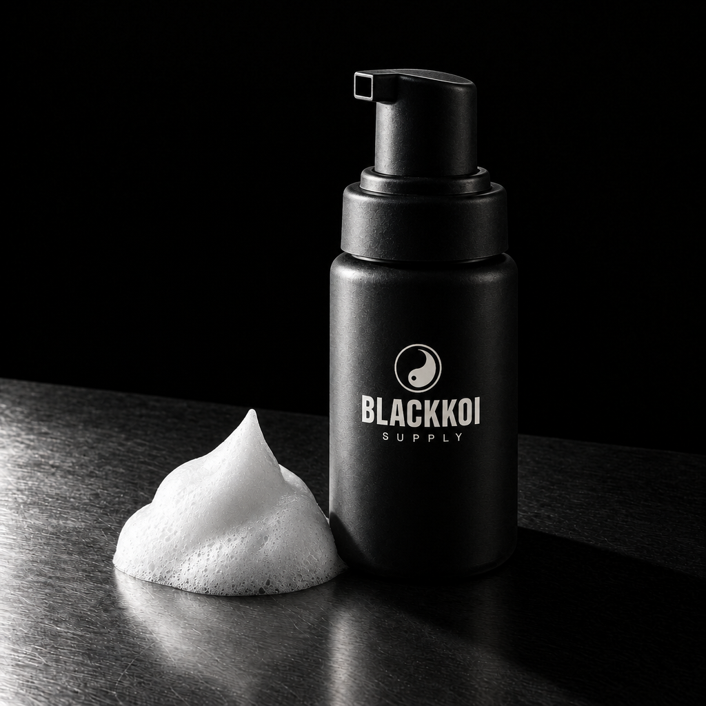 Aftercare foam cleanser, 60 ml pump bottle in BlackKoi Supply packaging, with a mound of foam